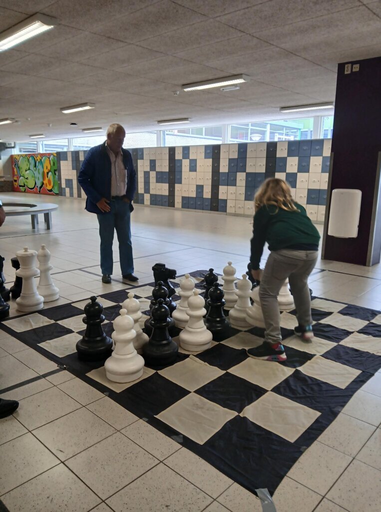 Jos Visser demonstreert het paardenspel aan een beginnende jeugdschaker (foto EvB)